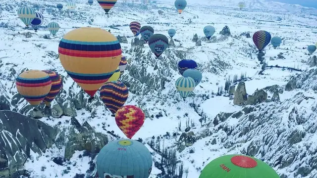 Hot air balloons flying over snow-covered Cappadocia in winter