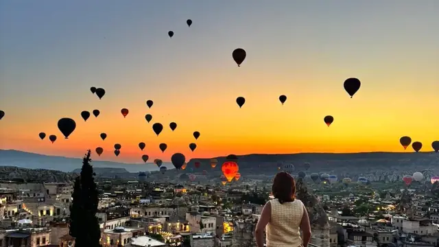 Traveler watching hot air balloons over Goreme from a Cappadocia terrace