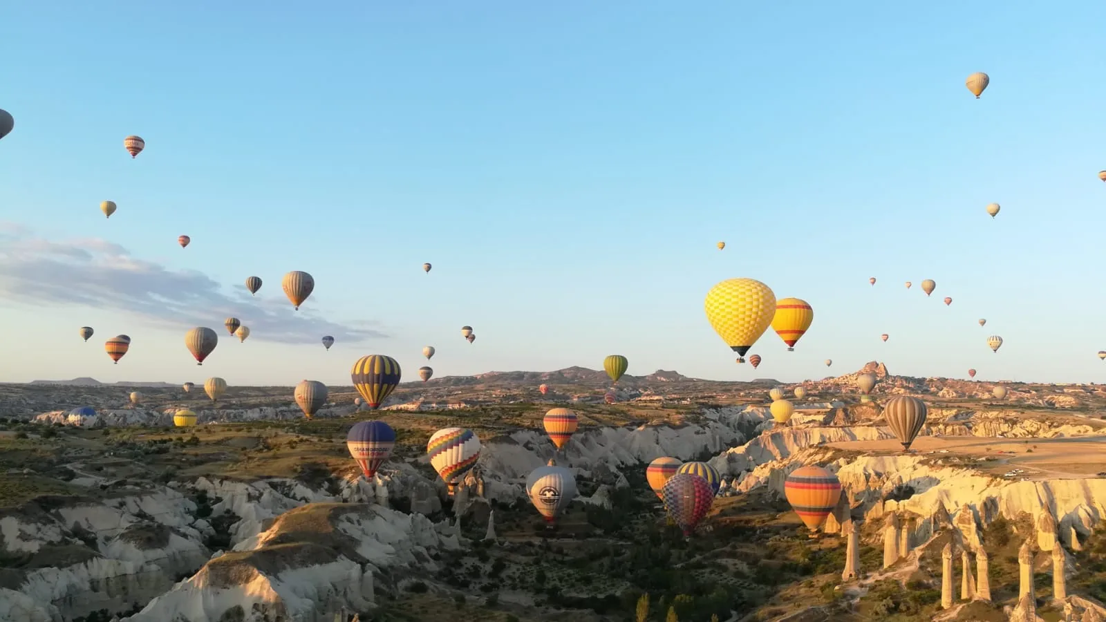 Hot air balloons flying through the valleys of Cappadocia at sunrise