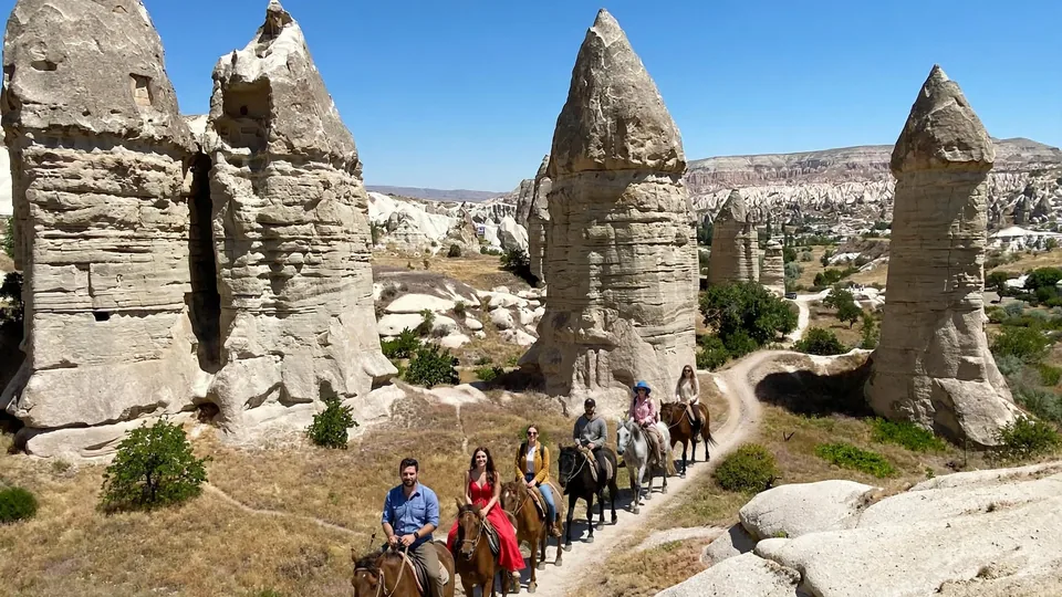 Travelers riding horses through Cappadocia fairy chimneys