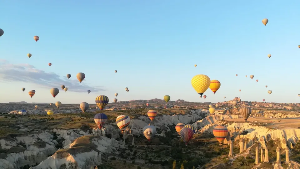 Hot air balloons flying across the Cappadocia valleys in the morning