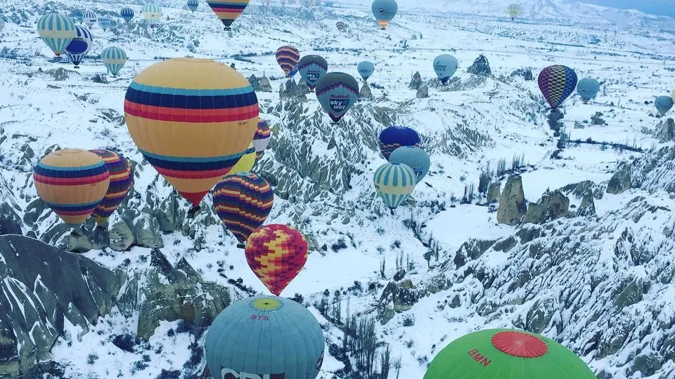 Hot air balloons flying over snow-covered Cappadocia in winter
