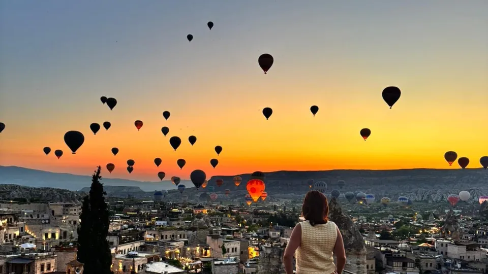 Traveler watching hot air balloons over Goreme from a Cappadocia terrace