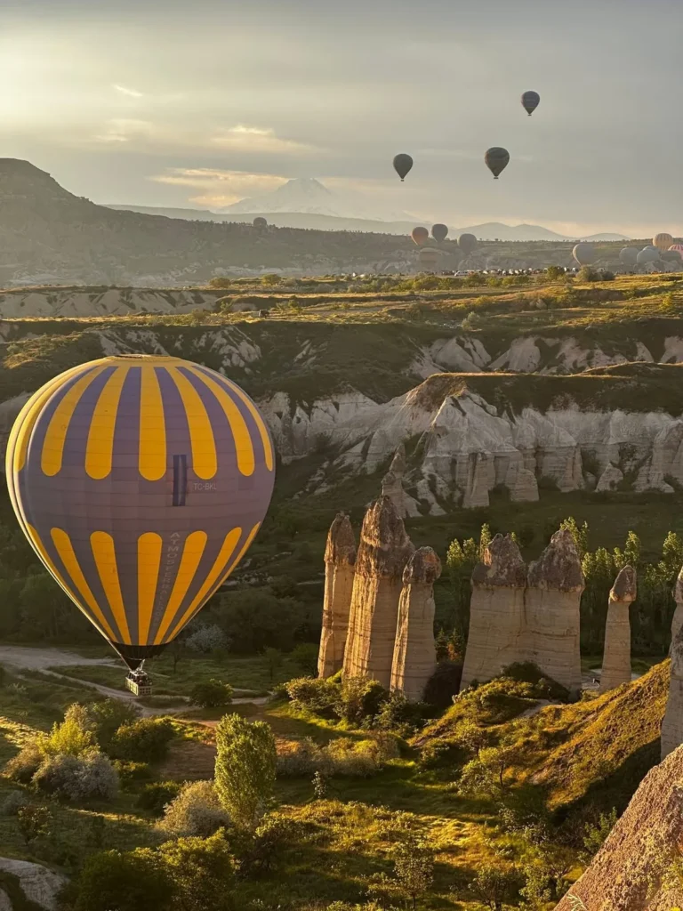 Hot air balloon flying beside fairy chimneys in Cappadocia