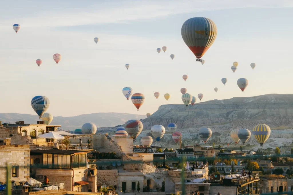 Hot air balloons flying above a Cappadocia town at sunrise